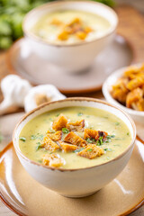 Garlic cream soup with bread croutons in rustic bowl