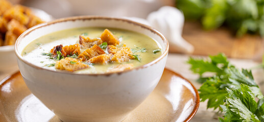 Garlic cream soup with bread croutons in rustic bowl