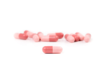 Obraz na płótnie Canvas Isolated gel capsules. Multiple pink softgel capsules randomly placed. Used to administer drugs, medicine, supplements or oil for people or pets. Selective focus on one capsule in front.
