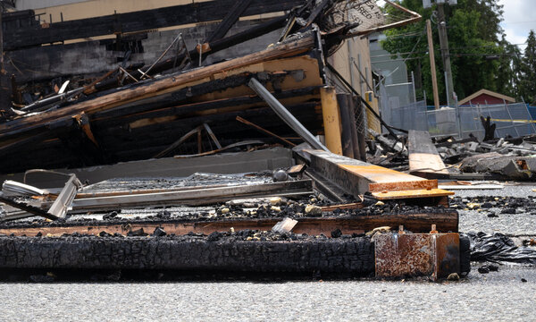 Burned building close up. Charred collapsed structure with wood beams. Total loss and collapse of building burned to the ground. Selective focus.