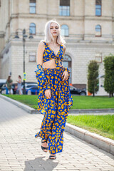 Young beautiful blonde woman in a stylish spotted summer suit walks around the city