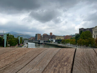 Fototapeta premium view of the immense river of bilbao from the wooden bridge on a cloudy day