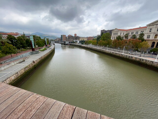 Obraz premium view of the immense river of bilbao from the wooden bridge on a cloudy day