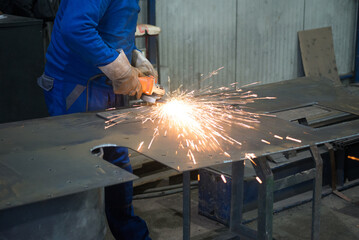 Construction worker cutting steel plates using plasma cutter in construction factory