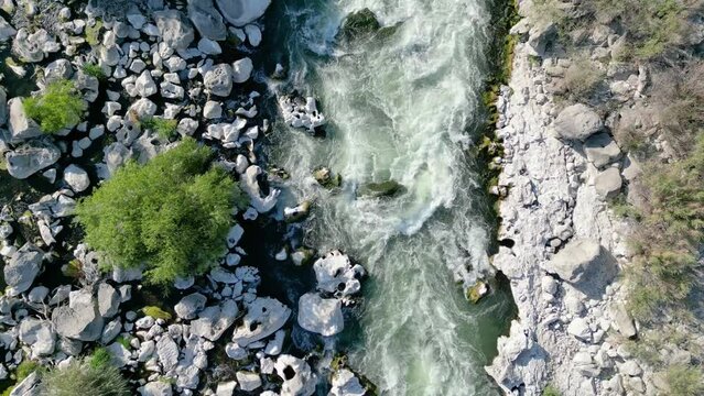 Aerial footage of a river rushing through white sun bleached rocks. Location, Snake River, Twin Falls Idaho.