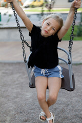 Portrait of a cute child on a swing at the playground.