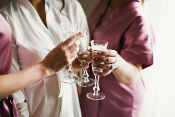 Photo bride with her friends drinking champagne from glasses