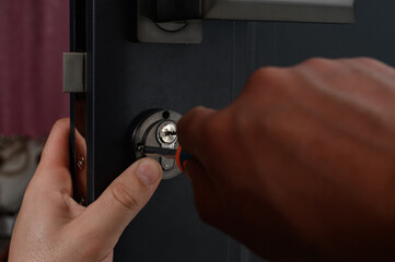 Installation of a door lock, a carpenter installs a door lock in a door, work close-up.