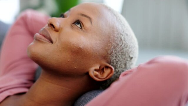 Relax, calm and mental health with a black woman lying on the couch to rest and free her mind at home. Closeup face of a beautiful african female feeling content and happy while relaxing on weekend