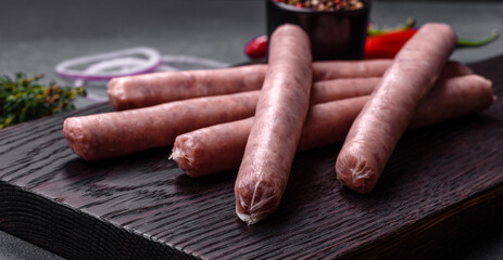 Raw sausages with spices on a wooden cutting board on a stone background with copy space for your text