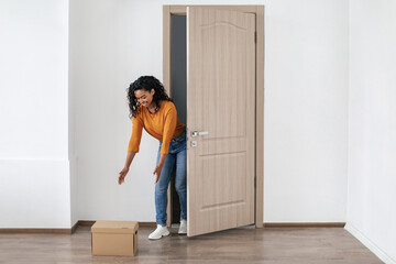 Fototapeta na wymiar African Lady Receiving Box Standing Near Opened Door At Home