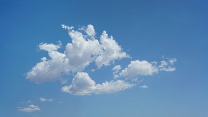 Isolated puffy clouds and blue sky for background use or sky substitution