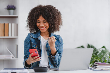 successful and exciting african american businesswoman Young woman excited to win on her smartphone...