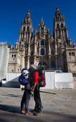 A couple of pilgrims celebrate in front of the cathedral of Santiago that they have reached the end...