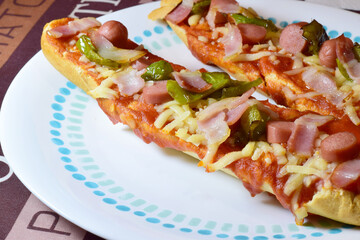 Panini, pizza bread, with mozzarella, tomato sauce, frankfurt, beacon and strips of green pepper.