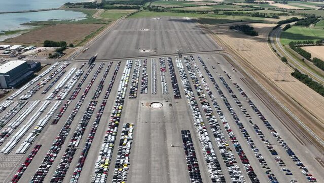Top down aerial view of import and export car automobile storage in harbour port. Automotive industry new vehicles parked lot ready for shipping. Economy business export.