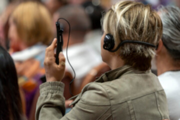 Blurry background, a set of headphones for simultaneous translation during negotiations in foreign languages. woman headphones used for simultaneous translation equipment simultaneous interpretation  - obrazy, fototapety, plakaty