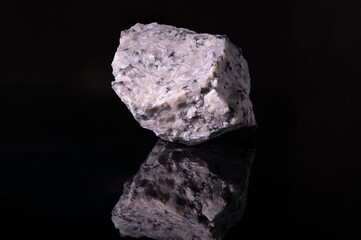 A fragment of the raw mineral albite gray with black inclusions