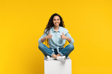 Young woman showing thumb up gesture, recommending or approving something, giving positive feedback