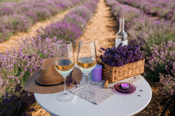 Two Glasses of white wine and bottle in a lavender field in Provance. Violet flowers on the background