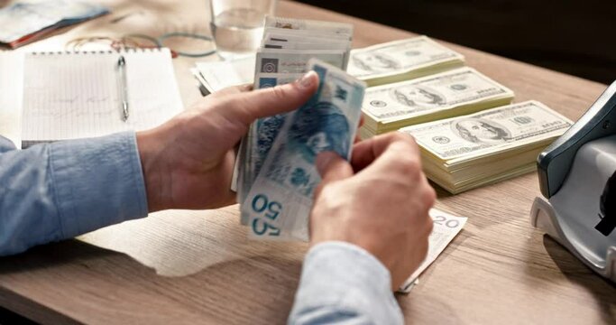 Close up of male accountant counting many polish banknotes while sitting at desk in cabinet. Man holding and calculating savings in cash. Business. Money concept. Bank and banking. Polish zloty