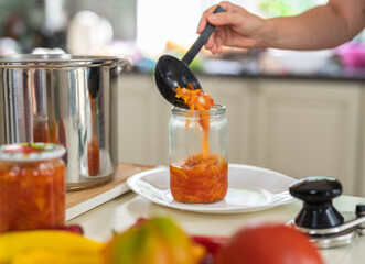 Home canning of vegetables. A woman in close-up preserves a vegetable salad in a glass jar