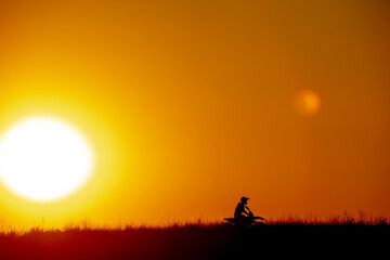 Fototapeta na wymiar motocross at sunset silhouette of a motorcycle on the field