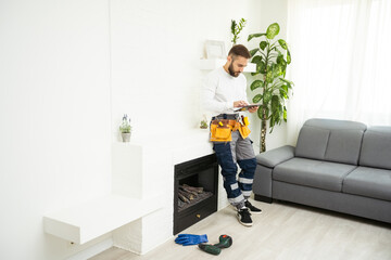 Naklejka premium Professional technician with screwdriver installing electric fireplace in room