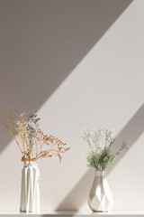 Dried pink and yellow flowers in white vase against white wall. Home interior autumn decor banner