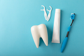 Toothbrush and toothpaste with tooth model on blue background with copy space. Flat lay. Oral...