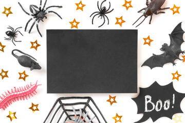 Black paper sheet on Halloween background with bats, spiders and golden stars. Modern Holiday Mock up. Halloween party invitation. Flat lay, top view, copy space. Thanksgiving fall decoration