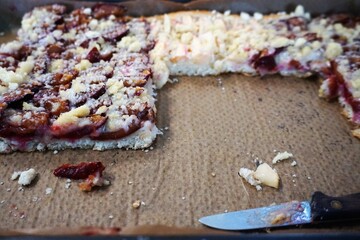 Blech mit Kuchen mit Pflaumen, Äpfeln und Streuseln und Messer 