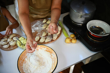 Top view. Cook sprinkles flour on dough to make homemade dumplings. Scene of artisanal food...