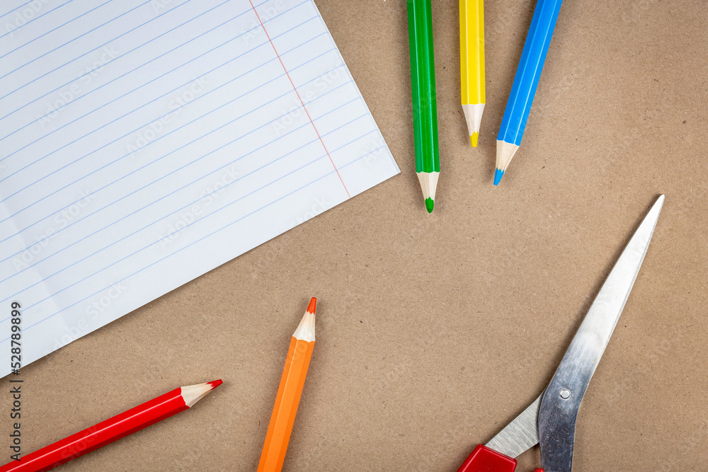 Poster school supplies and a notebook lie on a textured brown paper background