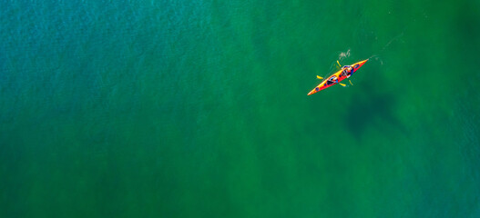 Red kayak boat two rowers on blue turquoise water sea, sunny day. Concept teamwork for business plan, aerial top view © Parilov