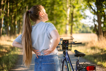 back pain, cramps after cycling girl in jeans - obrazy, fototapety, plakaty