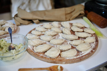 Selective focus on homemade dumplings, Ukrainian varenyky on a wooden board in the rustic summer country kitchen