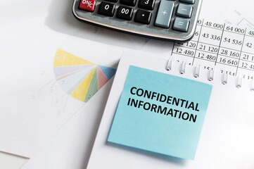 confidential information text on a blue card is pasted on a notebook on an office desk