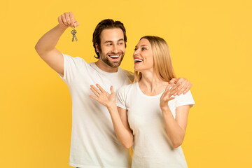 Glad happy millennial caucasian man show keys to excited woman in white t-shirts