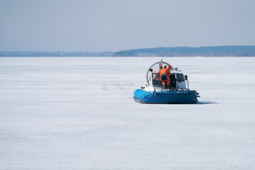 Lifeguard on an airboat on the coast of a frozen reservoir. Copy space.