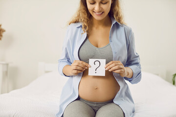 Happy mom-to-be thinking of name for her baby. Smiling pregnant lady trying to guess gender of...