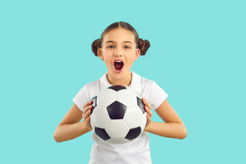 Funny girl child isolated on blue studio background hold ball cheer support sport team. Happy...