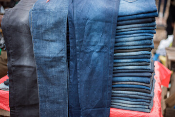 Men's jeans were displayed for sale in Lagos - Nigeria’s largest city, despite the rapidly increasing cost of living - clothes in a row - obrazy, fototapety, plakaty