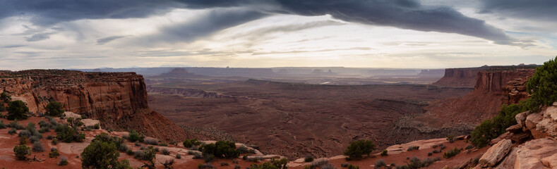 Fototapeta na wymiar Scenic Panoramic View of American Landscape and Red Rock Mountains in Desert Canyon. Cloudy Sunset Sky. Canyonlands National Park. Utah, United States. Nature Background Panorama