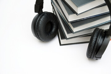 Black headphones with stack of books on light background.
