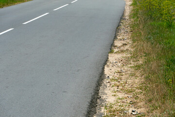 Empty asphalt road close-up against the sky. Empty background, space for text. New asphalt concrete pavement in rural areas.
