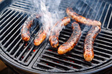 Barbecue Allgäu bratwurst offered as close-up on a charcoal grill with fire and smoke