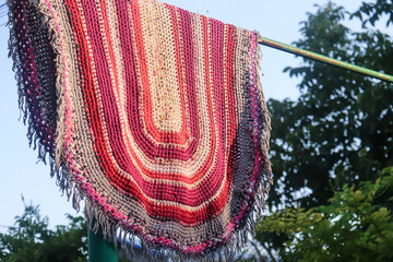 multi-colored woven rug from recycling fabric hanging after washing in the fresh air on a summer...