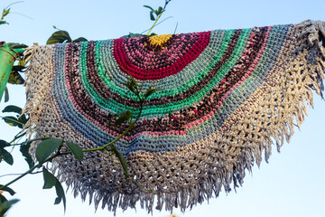 multi-colored woven rug from recycling fabric hanging after washing in the fresh air on a summer...