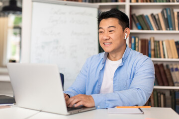 Korean Teacher Man Typing On Laptop Preparing Online Lecture Indoors